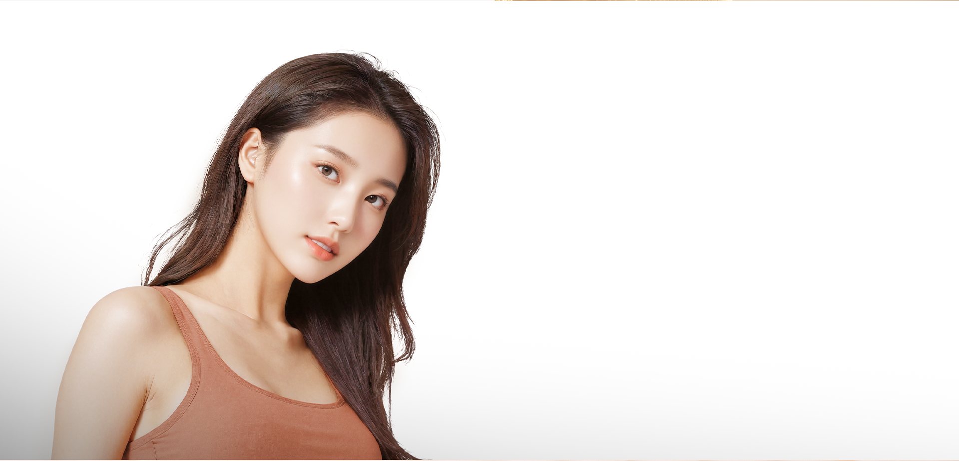 긴 생머리에 오렌지 브라운 톱을 입은 맑은 피부의 여성